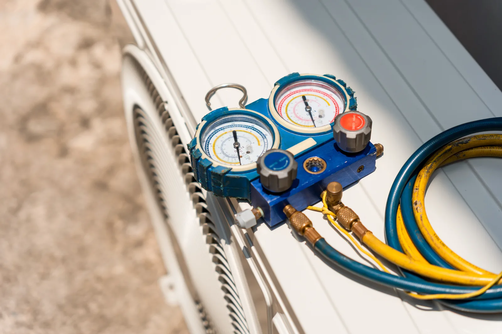 HVAC manifold gauge set used to diagnose refrigerant pressure on an AC unit